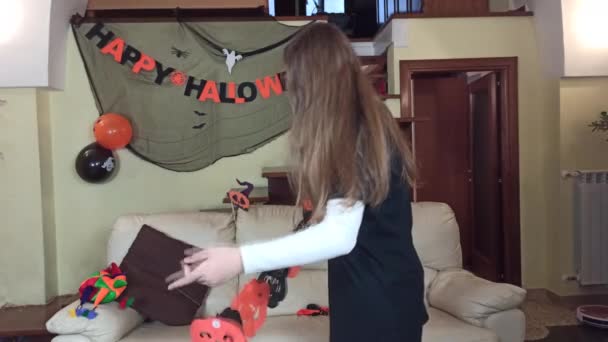 紙のマスクを作っている女の子は、自宅でハロウィーンの準備をし、お祝いの装飾で自宅でハロウィーンを祝います - 映像、動画