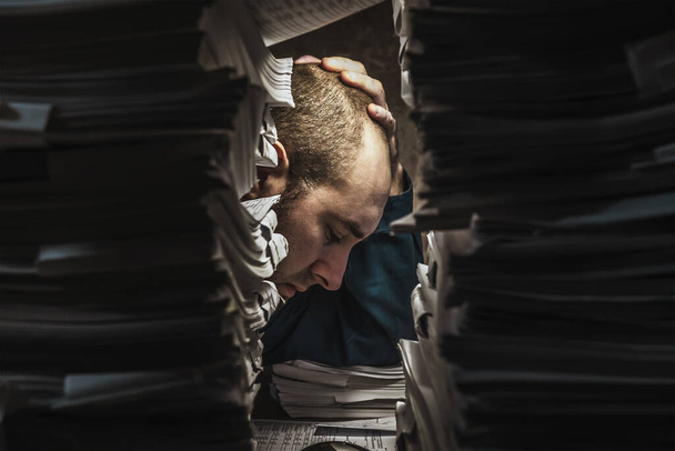 unavená pracovnice se s dokumenty vypořádává pozdě večer, sklání se nad nimi - Fotografie, Obrázek