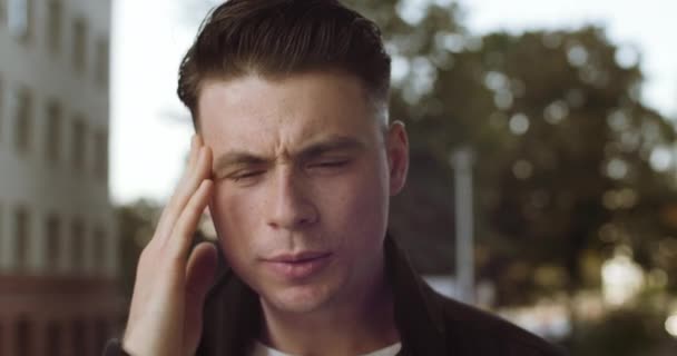 Portret van een verdrietig mannelijk gezicht, close-up van een man man met hoofdpijn migraine voelt pijnlijke toestand hoofdpijn, student voelt zich ziek hoofd vasthouden met handen, wrijft zijn slapen met de vingers, close-up - Video