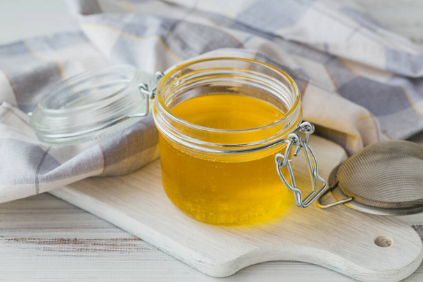 Healthy homemade Ghee or clarified butter in a jar on white wooden table. Healthy Ayurveda food concept. - Φωτογραφία, εικόνα
