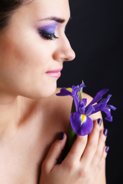 schöne junge Frau mit Blume auf dunklem Hintergrund - Foto, Bild