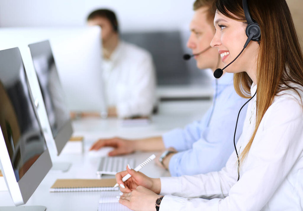 Call center. Group of diverse operators at work. Focus on beautiful asian woman in headset at customer service office. Business concept - Photo, Image