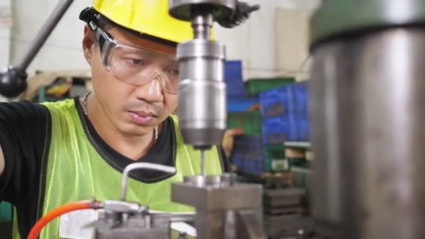 Крупным планом, ориентированным на азиатских рабочих, работает буровая машина, работающая с защитными очками и шлемом на производственной линии по производству листового металла. Камера Долли вид сбоку от машины - Кадры, видео