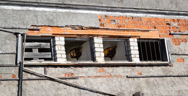 Внешняя стена с рядом разрушенных окон. Внутри остатки ржавой ванной. Заброшенное здание, близкое к сносу. Здание расположено на вершине горы Граппа (Италия)) - Фото, изображение