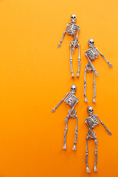 Az ezüst és arany csontvázak narancssárga alapon táncolnak. Halloween és a holtak napja koncepció - Fotó, kép