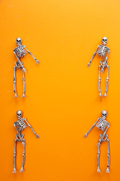 Σκελετοί σε ασήμι και χρυσό χορεύουν σε πορτοκαλί φόντο. Απόκριες και Ημέρα των Νεκρών έννοια - Φωτογραφία, εικόνα