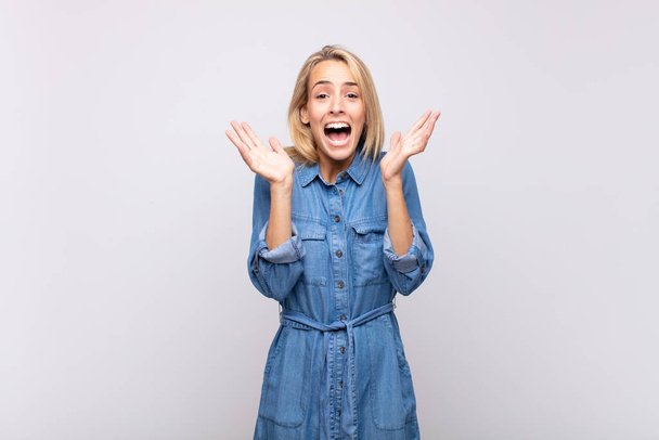 Woman looking happy and excited, shocked with an unexpected surprise with both hands open next to face - Photo, Image