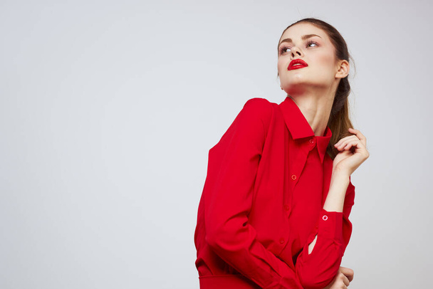 A beautiful girl with red lips and a shirt on a light background gestures with her hands - Fotografie, Obrázek