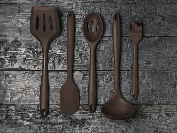 Five kitchen silicone accessories on a black wooden background. - Photo, Image
