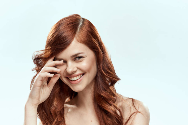 Όμορφη γυναίκα κρατώντας τα μαλλιά χαμόγελο καλλυντικά lifestyle γυμνοί ώμοι hairstyle φροντίδα γοητεία φως φόντο - Φωτογραφία, εικόνα