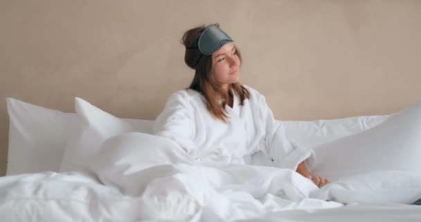 Hübsche Frau dehnt sich auf bequemem Bett mit Kissen - Filmmaterial, Video