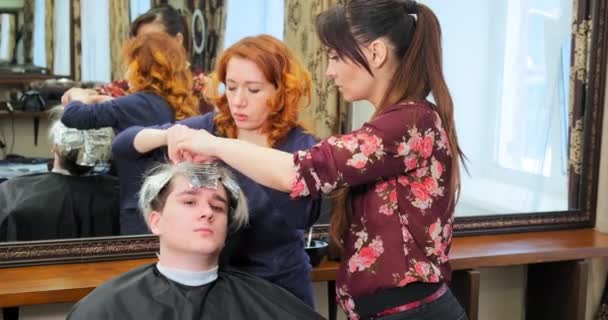 coiffeurs prennent du papier d'aluminium avec de l'eau de Javel à partir de cheveux gars sérieux - Séquence, vidéo
