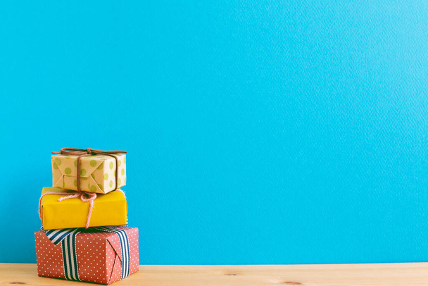 Colorful gift boxes on wooden table with blue background - Zdjęcie, obraz