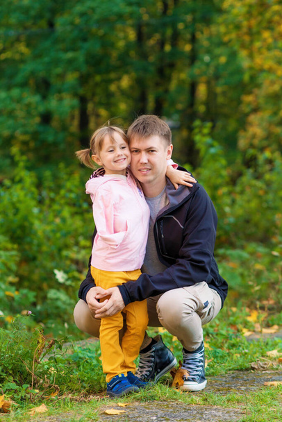 .A girl with a broken arm hugs her dad in an old park on an autumn walk. - Valokuva, kuva