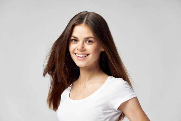 Glückliche Frau mit lockerem Haar im weißen T-Shirt mit schönem Lächeln - Foto, Bild