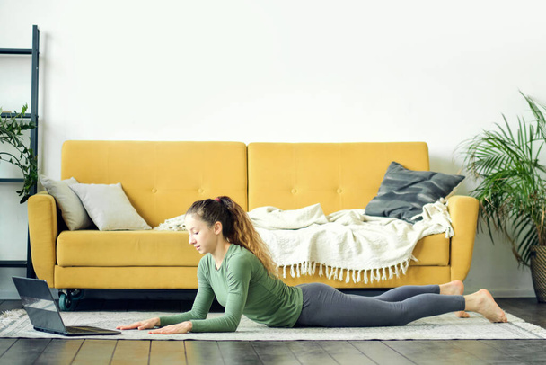 Mulher bonita fazendo ioga em casa. Treinamento de fitness online. - Foto, Imagem