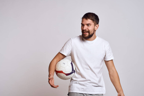 mężczyzna trener z piłka nożna w jego ręce na lekkim tle energia wyjaśnienie ruchy - Zdjęcie, obraz