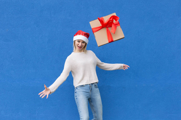 the Girl on a blue background with a New Year's gift - Фото, изображение
