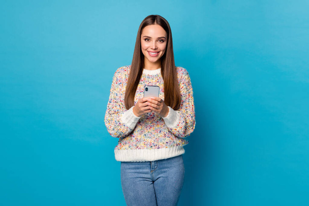 Photo of beautiful attractive lady long straight hairdo hold telephone hands online freelance work quarantine read news wear casual sweater jeans isolated blue color background - Fotoğraf, Görsel