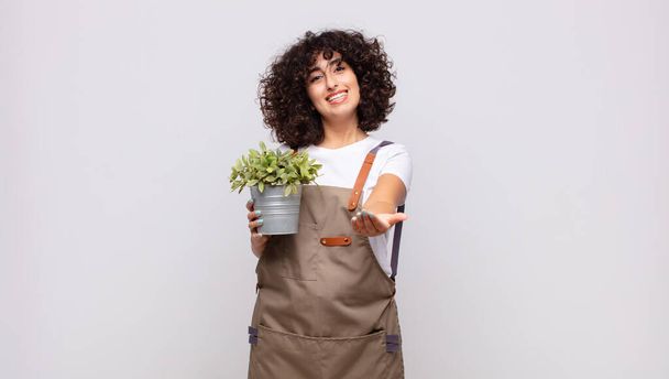 young woman gardener smiling happily with friendly, confident, positive look, offering and showing an object or concept - Foto, immagini