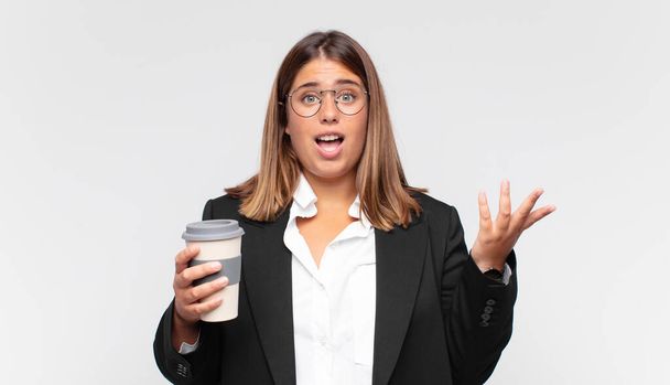young businesswoman with a coffee feeling happy, surprised and cheerful, smiling with positive attitude, realizing a solution or idea - Photo, image
