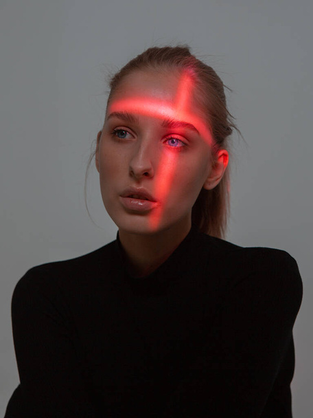 Studio portrait of young girl with cross shaped red light on her head - Foto, Bild