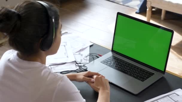 Una joven india dirige una conferencia en línea, entrenando con la gente, utiliza una computadora portátil con una pantalla verde. Habitación luminosa en casa - Imágenes, Vídeo