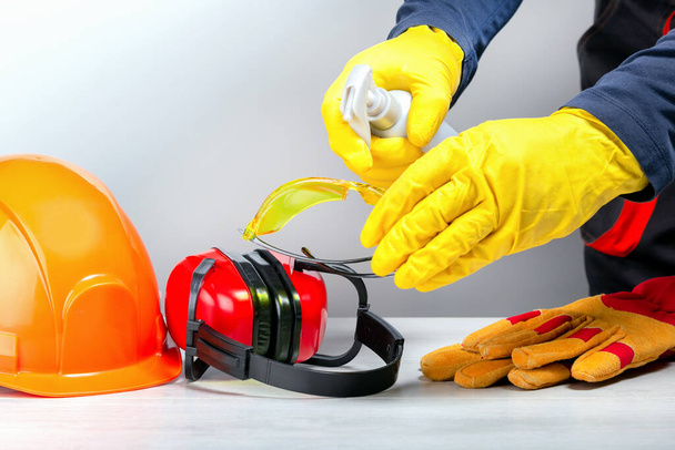 Builder disinfecting protective clothing in workplace. Coronavirus treatment concept. - Zdjęcie, obraz