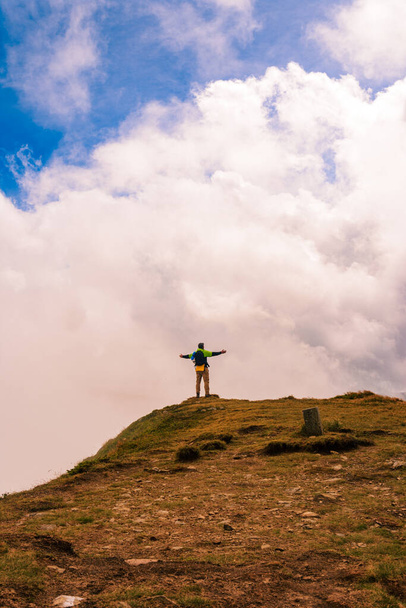 Um turista no topo da montanha abriu os braços como um pássaro, desfrutando da altura e majestade das montanhas. - Foto, Imagem