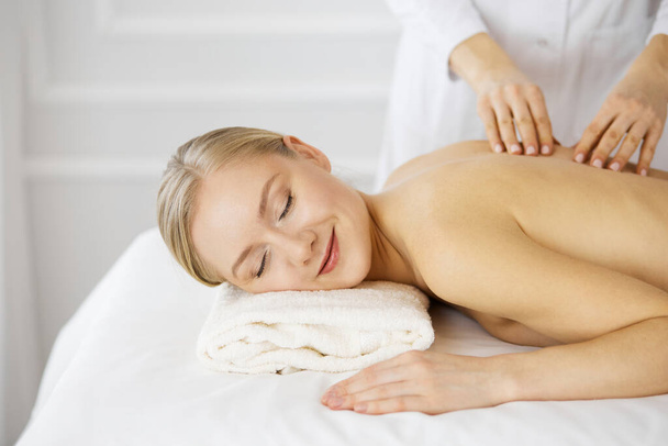 Beautiful caucasian woman enjoying back massage with closed eyes. Beauty and Spa salon concept - Фото, зображення