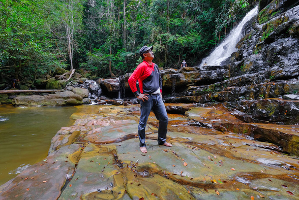 A man is posing in front of Waterfall. - Zdjęcie, obraz