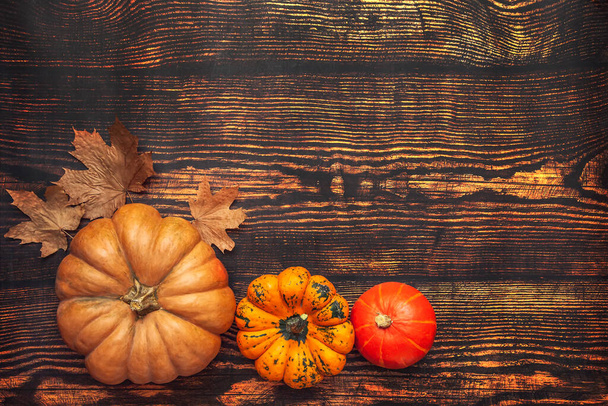 Wooden background with pumpkins and maple leaves, flatlay with copy space. - Photo, Image
