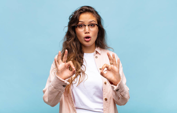 Woman feeling shocked, amazed and surprised, showing approval making okay sign with both hands - Photo, image