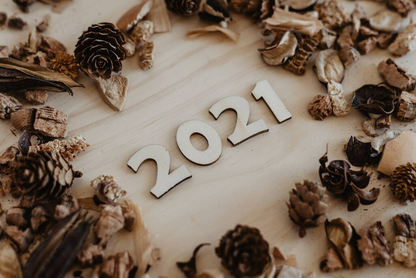 2021 pongan en la parte superior de la mesa los números de madera con los frutos secos y las flores alrededor - Foto, imagen