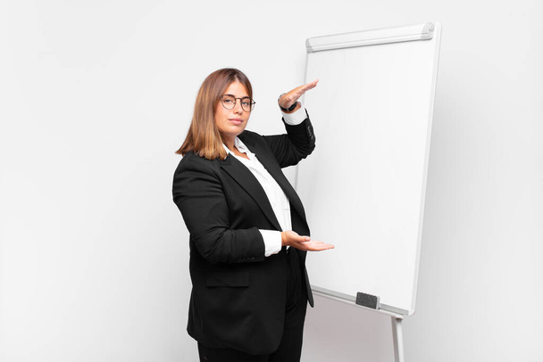 Женщина держит объект обеими руками на боковом копировальном пространстве, показывая, предлагая или рекламируя объект - Фото, изображение