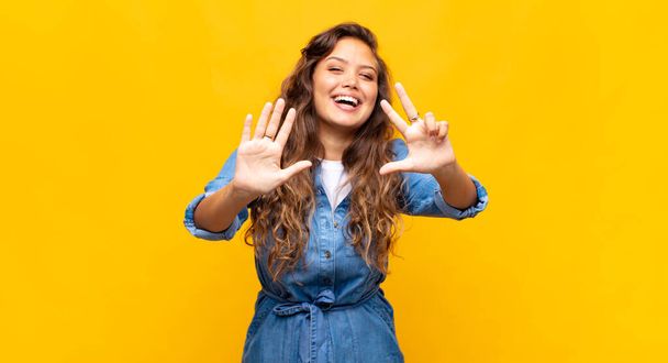 Woman smiling and looking friendly, showing number eight or eighth with hand forward, counting down - Foto, Imagen