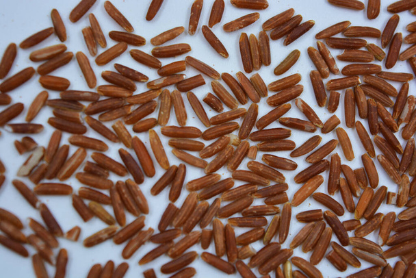 Heerlijke en gezonde rode lange wilde rijst besprenkeld op een witte plaat. Gezonde voeding, gezonde granen voor elke dag is natuurlijke rijst. - Foto, afbeelding