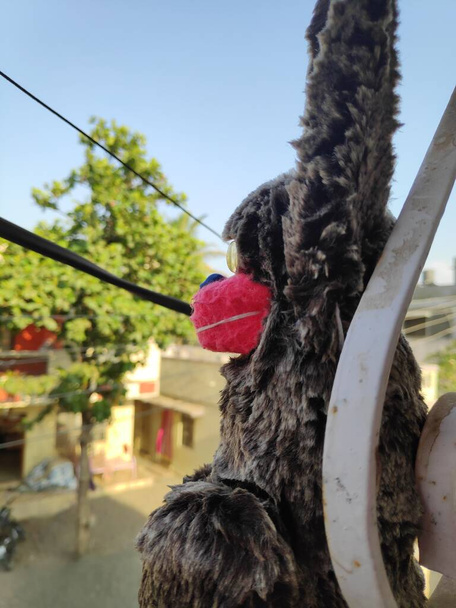 zwarte aap met rood gezicht gevulde speelgoed opknoping out in balkon in bokeh wazig - Foto, afbeelding