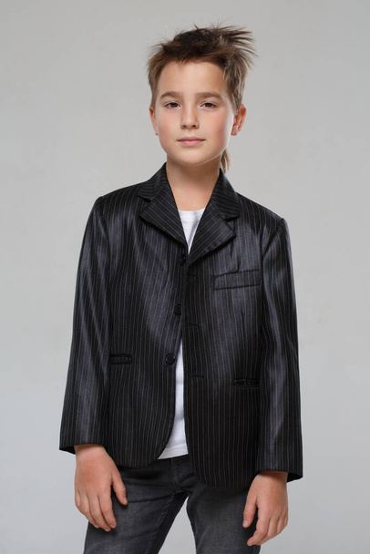 Little stylish boy in a jacket isolated on a gray background. - Фото, изображение