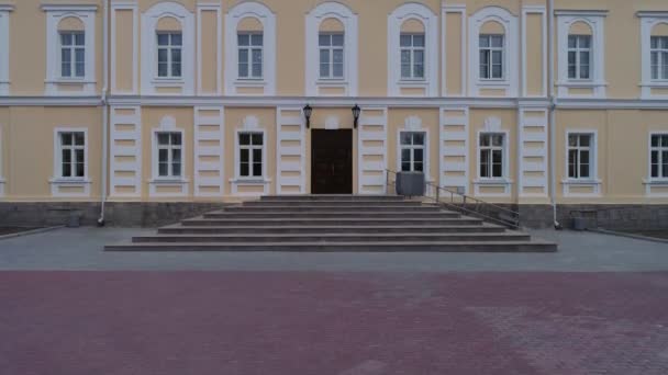 Pohled na renovovanou historickou administrativní budovu (škola, tělocvična, ústav). Světle žlutá fasáda s bílými okny. Kamera jede nahoru - Záběry, video