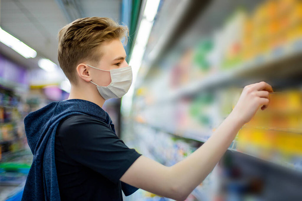 Junge trägt Schutzmaske im Geschäft. Einkaufszeit während des Coronavirus-Ausbruchs. Junge in medizinischer Maske. Quarantäne- und Schutzvirus, Grippe, Epidemie COVID-19. Coronavirus-Quarantäne. - Foto, Bild