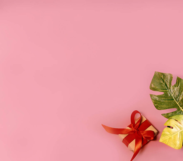 banner κουτί δώρου σε ροζ φόντο με monstera αφήνει διακοπές έννοια top view αντίγραφο χώρο για την κάρτα κειμένου - Φωτογραφία, εικόνα