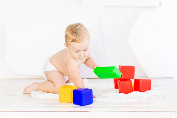Küçük bir çocuk. Altı aylık bir çocuk parlak beyaz bir odada parlak küplerle oynuyor. - Fotoğraf, Görsel