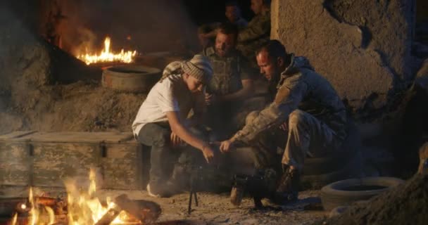 Soldiers and teenager resting near campfire - Footage, Video