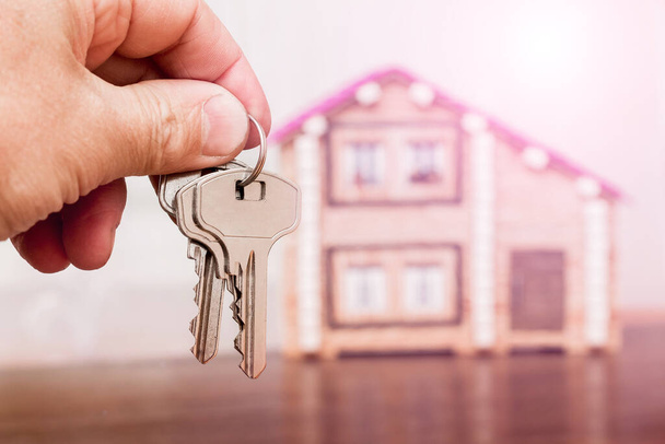 Мужчина держит ключи на заднем плане нового дома. Продажа и покупка домов - Фото, изображение