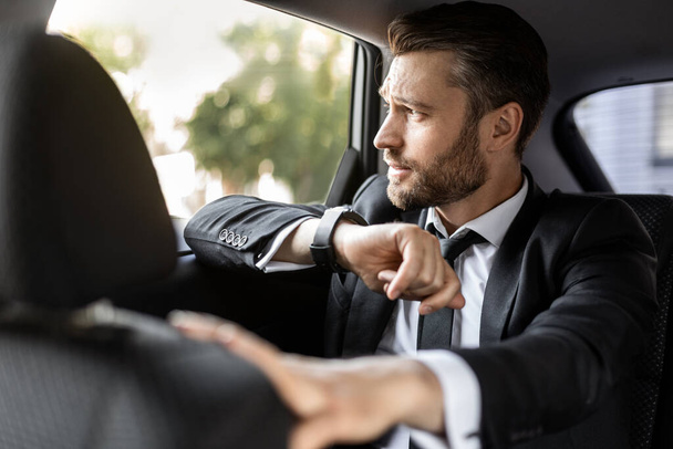 Hezký vousatý muž v obleku sedí v autě - Fotografie, Obrázek