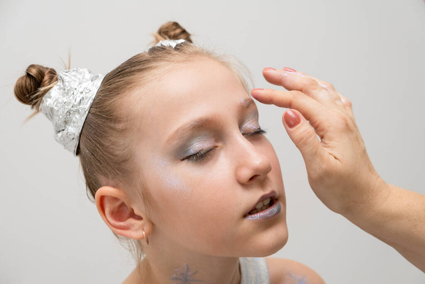 makeup artist makes a festive shining makeup for beautiful young girl. makeup for Halloween or new year. - Fotó, kép