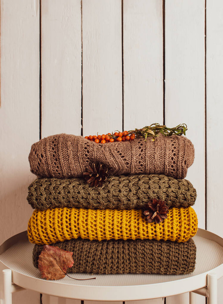 A stack of warm knitted vintage sweaters on a white wooden background. Autumn concept - Foto, immagini