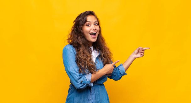 Woman feeling joyful and surprised, smiling with a shocked expression and pointing to the side - Photo, Image