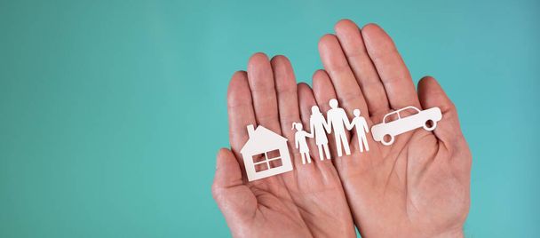 Concepto de vida, seguro de automóvil y hogar con familia de papel, coche y casa en manos sobre fondo de color turquesa - Foto, imagen